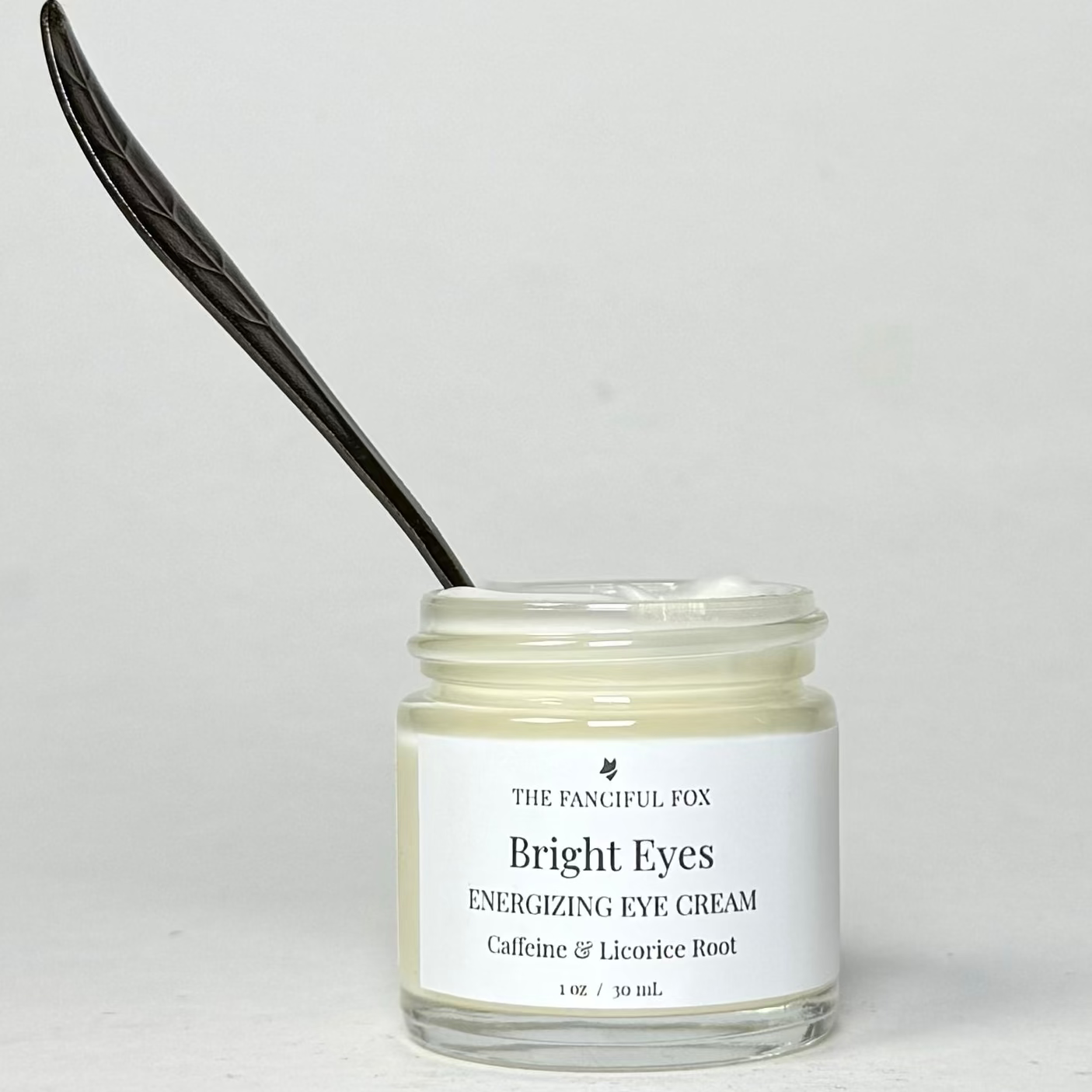 Jar of 'Bright Eyes' eye cream with a black applicator on a light gray background