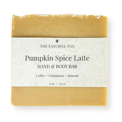 A single bar of hand and body soap wrapped in a white paper label. The soap has a warm pumpkin spice color, and the label reads 'THE FANCIFUL FOX' and 'Pumpkin Spice Latte HAND & BODY BAR'.