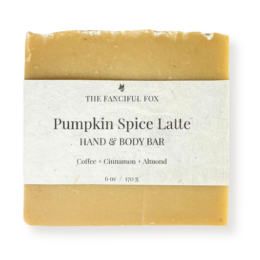 A single bar of hand and body soap wrapped in a white paper label. The soap has a warm pumpkin spice color, and the label reads 'THE FANCIFUL FOX' and 'Pumpkin Spice Latte HAND & BODY BAR'.
